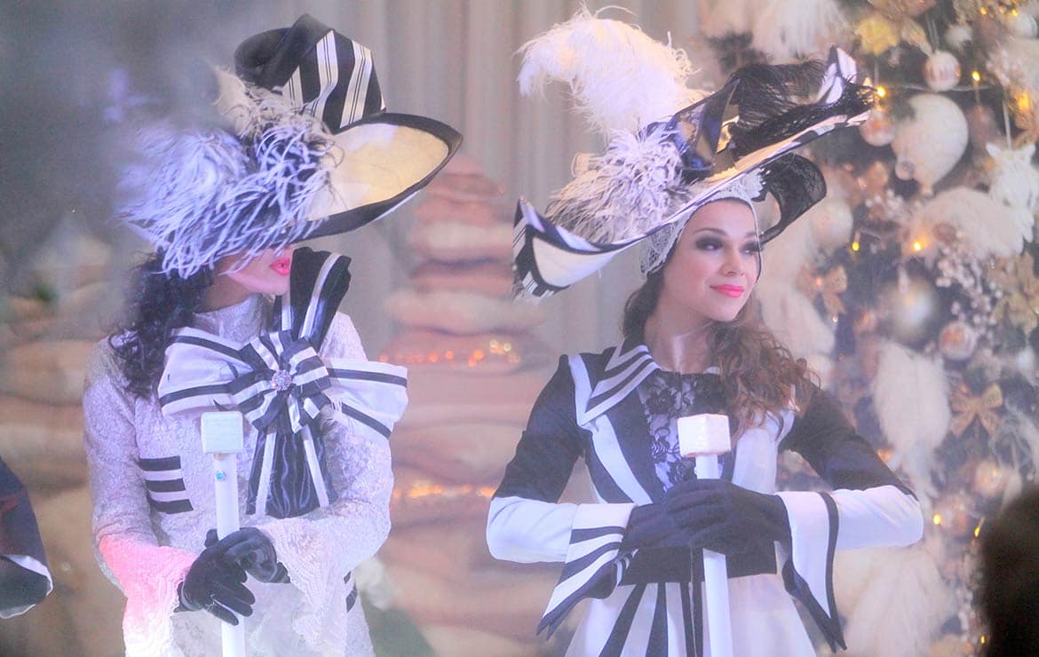 Show performers in black-and-white costumes and wide-brimmed hats