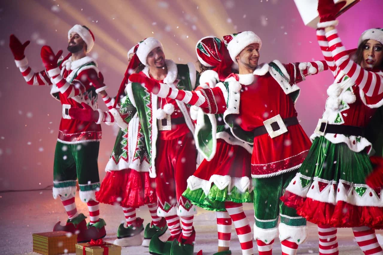 Festive cast in red and green celebrating on stage